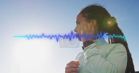 Téléchargez les photos : Image de traînée bleue sur une femme biraciale portant des écouteurs. concept de santé et de fitness image générée numériquement. - en image libre de droit