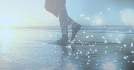 Manchas azules brillantes de luz contra la sección baja de una mujer caminando por la playa. Concepto de amor y relación