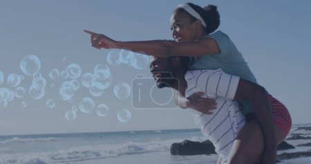 Foto de Imagen de burbujas sobre una sonriente pareja afroamericana. concepto de interfaz digital y deporte global imagen generada digitalmente. - Imagen libre de derechos