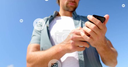 Téléchargez les photos : Image d'icônes de courrier au-dessus du milieu de l'homme caucasien utilisant un smartphone à l'extérieur. connexions mondiales, médias sociaux, technologie et concept d'interface numérique image générée numériquement. - en image libre de droit
