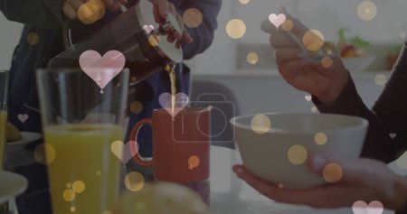 Foto de Imagen de corazones sobre pareja femenina caucásica desayunando. San Valentín, amor y celebración concepto de imagen generada digitalmente. - Imagen libre de derechos
