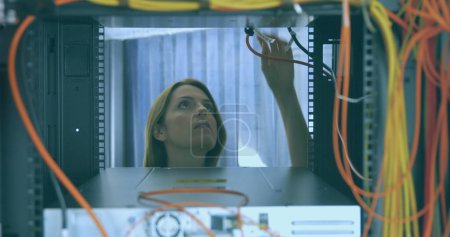 Téléchargez les photos : Une femme caucasienne examine les câbles du serveur dans un centre de données. Elle se concentre sur l'entretien ou le dépannage de l'infrastructure réseau sur son lieu de travail.. - en image libre de droit