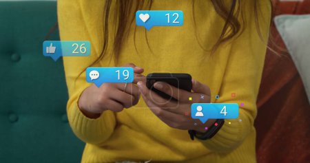 Image of social media reactions over hands of caucasian woman using smartphone. Social media, network, communication and technology concept digitally generated image.