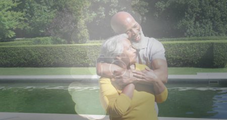 Image of glowing spots over happy african american senior couple cuddling. senior life, retirement and golden years concept digitally generated image.