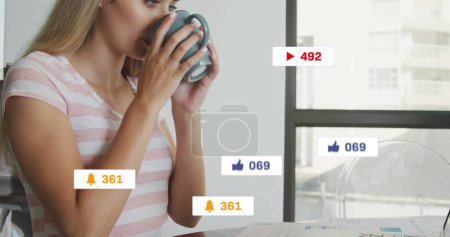 Téléchargez les photos : Image d'icônes des médias sociaux sur des bannières sur une femme caucasienne buvant du café à l'aide d'un ordinateur portable. médias sociaux, interface numérique et concept de connexions image générée numériquement. - en image libre de droit