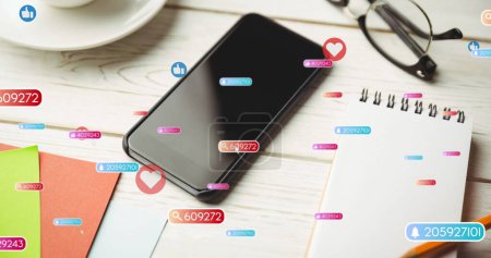 Image of social media like and love icons over smartphone on desk background. Global social media, connections, communication and digital interface concept digitally generated image.