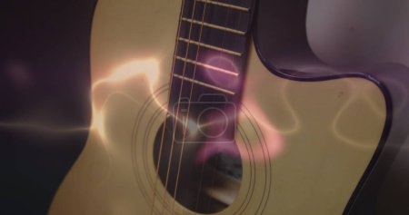 Photo for Image of white, blue and pink light trails over acoustic guitar on smokey background. Music, creativity, performance and entertainment concept digitally generated image. - Royalty Free Image