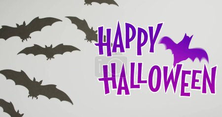 Téléchargez les photos : Joyeux halloween texte bannière avec icône de chauve-souris contre plusieurs jouets de chauve-souris sur la surface grise. fête d'Halloween et concept de célébration - en image libre de droit