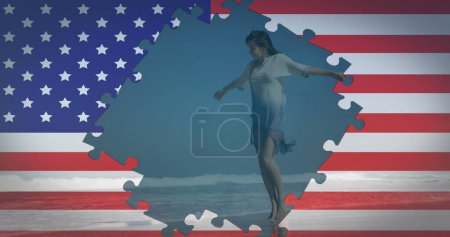 Téléchargez les photos : Image du drapeau américain agitant avec des puzzles révélant une femme dansant sur la plage au bord de la mer pendant les vacances d'été en arrière-plan. American society diversity concept digital composition. - en image libre de droit