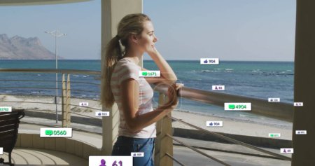 Imagen de iconos de redes sociales en pancartas sobre una relajada mujer caucásica admirando la vista junto al mar. redes sociales, interfaz digital y concepto de conexiones imagen generada digitalmente.
