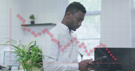 Foto de Imagen de un gráfico rojo sobre un hombre de negocios afroamericano usando un smartphone en la oficina. Comunicación global, negocios, inclusividad, datos e interfaz digital concepto de imagen generada digitalmente. - Imagen libre de derechos