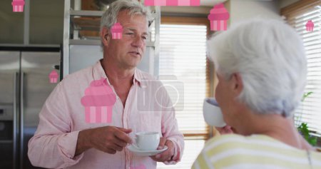 Photo for Image of pink fairy cakes over happy caucasian senior couple talking and drinking tea. retirement lifestyle, companionship and wellbeing concept digitally generated image. - Royalty Free Image