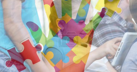 Téléchargez les photos : Image de pièces de puzzle et la main sur divers écoliers à l'aide d'une tablette. mois de sensibilisation à l'autisme et concept de célébration image générée numériquement. - en image libre de droit