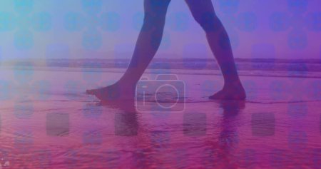 Téléchargez les photos : Modèle carré rose contre la section basse d'une femme marchant sur la plage. Concept d'amour et de relation - en image libre de droit