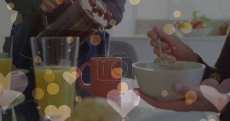 Téléchargez les photos : Image de coeurs sur le couple de femmes caucasiennes prenant le petit déjeuner. Valentines, amour et concept de célébration image générée numériquement. - en image libre de droit