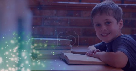 Téléchargez les photos : Image de taches lumineuses sur un livre de lecture de garçon caucasien souriant. Journée internationale de l'alphabétisation et concept de lecture image générée numériquement. - en image libre de droit