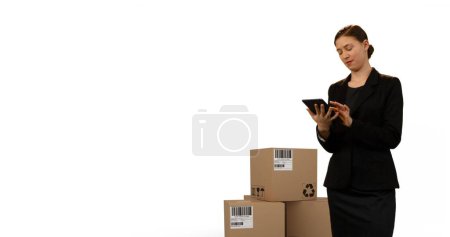 Téléchargez les photos : Image d'une femme tenant un comprimé avec des piles de boîtes sur fond blanc. concept global d'expédition, de livraison et de logistique image générée numériquement. - en image libre de droit