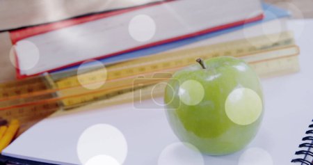 Image of white spots over apple and books. international literacy day and reading concept digitally generated image.