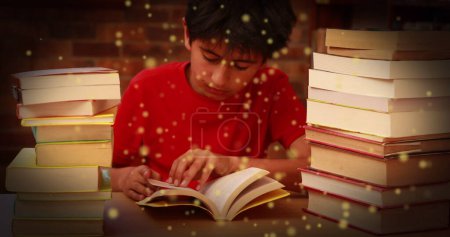 Foto de Imagen de manchas brillantes sobre un chico asiático leyendo un libro. Día internacional de la alfabetización y concepto de lectura imagen generada digitalmente. - Imagen libre de derechos