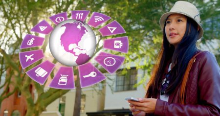 Image of travel icons with globe and biracial woman using smartphone in background. Global travel, technology, digital interface and data processing concept digitally generated image.