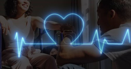 Imagen de ritmo cardíaco de neón y corazón sobre feliz pareja birracial, mujer en silla de ruedas. Imagen generada digitalmente del concepto de monitoreo de funciones de salud y vida.