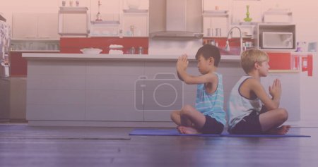 Téléchargez les photos : Asian and caucasian brothers performing yoga in the kitchen at home. national siblings day awareness concept - en image libre de droit