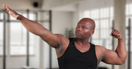 Foto de Vista frontal de un afroamericano moviendo los brazos y posando en el gimnasio - Imagen libre de derechos