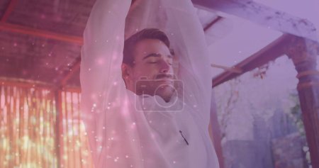 Bild von Lichtflecken über dem kaukasischen Mann, der Yoga praktiziert und meditiert. Weltmeditationstag und Festkonzept digital generiertes Bild.