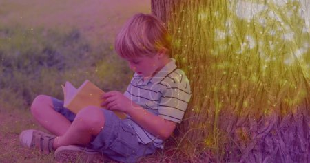 Photo for Image of glowing spots over caucasian boy reading book. international literacy day and reading concept digitally generated image. - Royalty Free Image