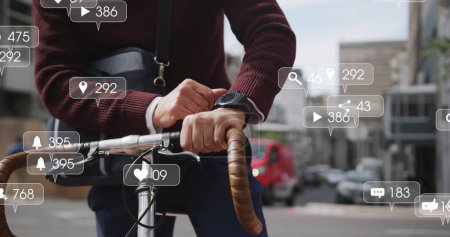 Téléchargez les photos : Homme caucasien vérifie sa montre intelligente tout en faisant du vélo, avec de l'espace de copie. Le cadre extérieur capture un moment d'intégration technologique dans la routine quotidienne de remise en forme. - en image libre de droit