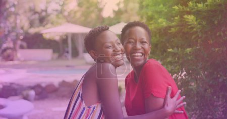 Téléchargez les photos : Two african american sisters hugging each other at a resort. national siblings day awareness concept - en image libre de droit