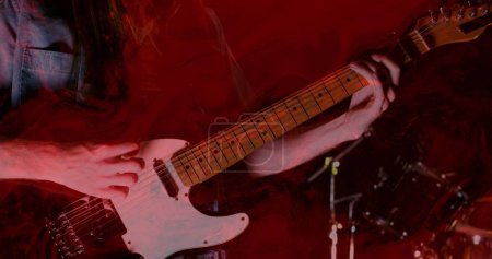 Téléchargez les photos : Image de lumières rouges incandescentes sur la partie médiane d'un homme caucasien jouant de la guitare. Concept de musique, performance et divertissement. - en image libre de droit