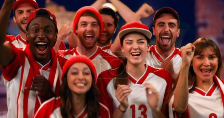 Foto de Vista frontal de entusiastas aficionados al deporte con camisetas rojas y blancas animando - Imagen libre de derechos