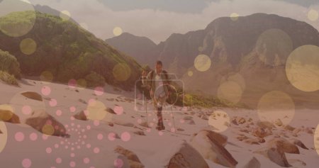 Photo for Image of light spots over disabled biracial man walking in mountains. walk day and celebration concept digitally generated image. - Royalty Free Image