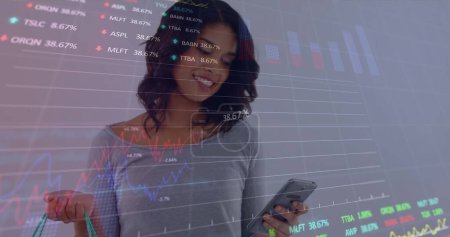Imagen de datos financieros y gráficos sobre la sección media de una mujer caucásica usando un teléfono inteligente. Finanzas, economía, comunicación y tecnología concepto de imagen generada digitalmente.