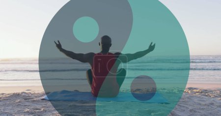 Foto de Imagen de ying yang símbolo sobre el hombre afroamericano mayor sentado en la playa soleada. concepto saludable y activo de vacaciones en la playa imagen generada digitalmente. - Imagen libre de derechos