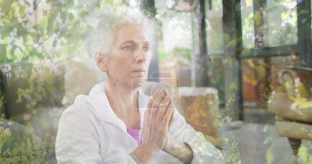 Téléchargez les photos : Image de feuilles sur une femme caucasienne âgée pratiquant le yoga et la méditation. Journée mondiale de méditation et concept de célébration image générée numériquement. - en image libre de droit
