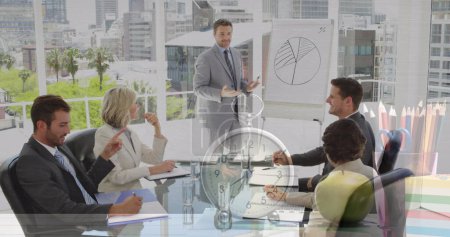 Image of clock over diverse business people at meeting. global business and digital interface concept digitally generated image.
