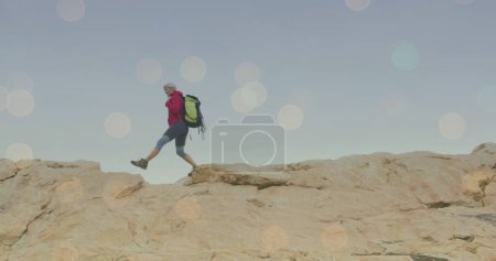 Photo for Image of light spots over caucasian woman walking in mountains. walk day and celebration concept digitally generated image. - Royalty Free Image
