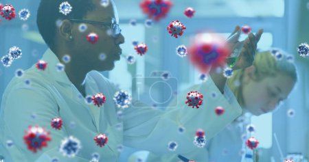 Foto de Imagen de células del coronavirus que fluyen sobre dos trabajadoras de laboratorio que examinan muestras de sangre. Covid 19 pandemia salud ciencia medicina concepto digital compuesto. - Imagen libre de derechos