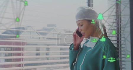 Bild einer asiatischen Ärztin mit Smartphone über Mediensymbolen. Globale Medizin, Finanzen, Verbindungen und digitales Schnittstellenkonzept digital generiertes Bild.