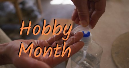 Image of hobby month text over caucasian man disinfecting hands. hobby and lifestyle concept digitally generated image.