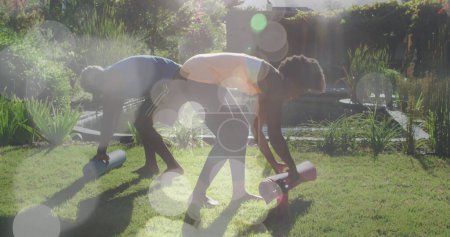 Téléchargez les photos : Image de taches lumineuses sur des tapis de yoga roulants de couple afro-américain, au ralenti. Concept de sport, fitness et santé image générée numériquement. - en image libre de droit