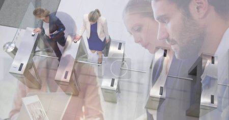 Image of diverse colleagues using laptops in office over commuters walking through turnstiles. business and communication technology concept digitally generated image.