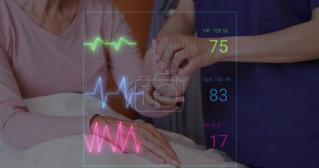 Image of medical vital signs data over female doctor examining hand of senior female patient. Medical and healthcare services concept digitally generated image.
