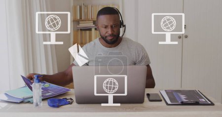 Téléchargez les photos : Image d'écrans avec des icônes globes sur un homme afro-américain utilisant un ordinateur portable. Concept mondial de médias sociaux, de communication, de connexions, d'informatique et de traitement de données image générée numériquement. - en image libre de droit