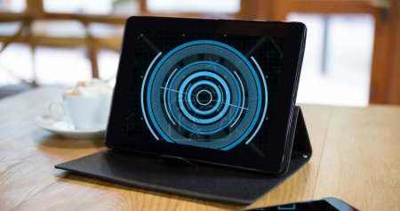 Photo for Image of blue circular scanner on black screen of tablet on table in cafe. Data, global communication and digital interface concept digitally generated image. - Royalty Free Image
