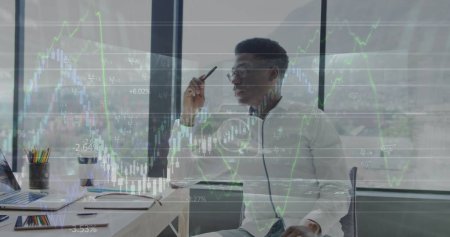Foto de Imagen de datos financieros sobre hombres de negocios afroamericanos que trabajan en computadoras portátiles en la oficina. economía, finanzas, negocios y tecnología concepto de imagen generada digitalmente. - Imagen libre de derechos