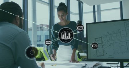 Image of connected icons over diverse architects discussing blueprint in office. Digital composite, multiple exposure, communication, report, business, planning, teamwork and technology concept.