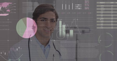 Image of financial data and graphs over happy biracial male doctor. Health, medicine, finance and economy concept digitally generated image.